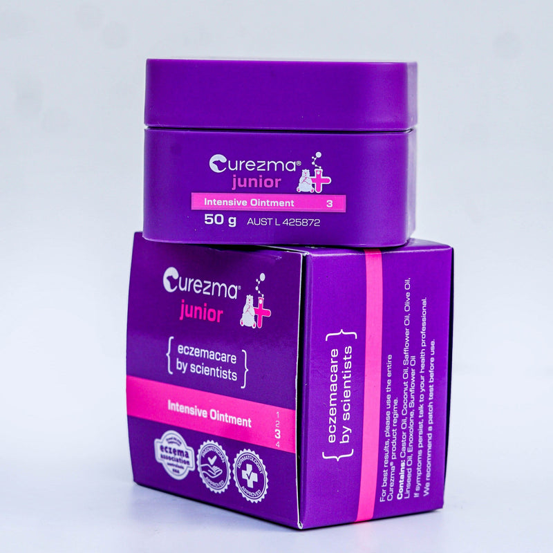 Purple jar and box of Curezma Junior Intensive Ointment on a light gray background
